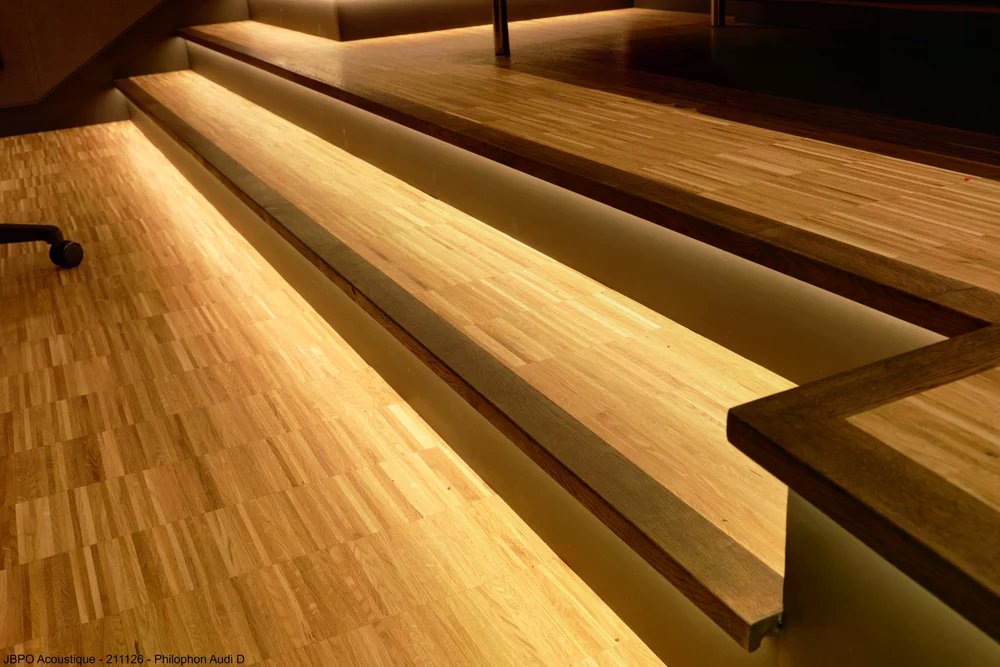 Philophon Audi D — détail estrade bois avec éclairage LED intégré, menuiserie TCS